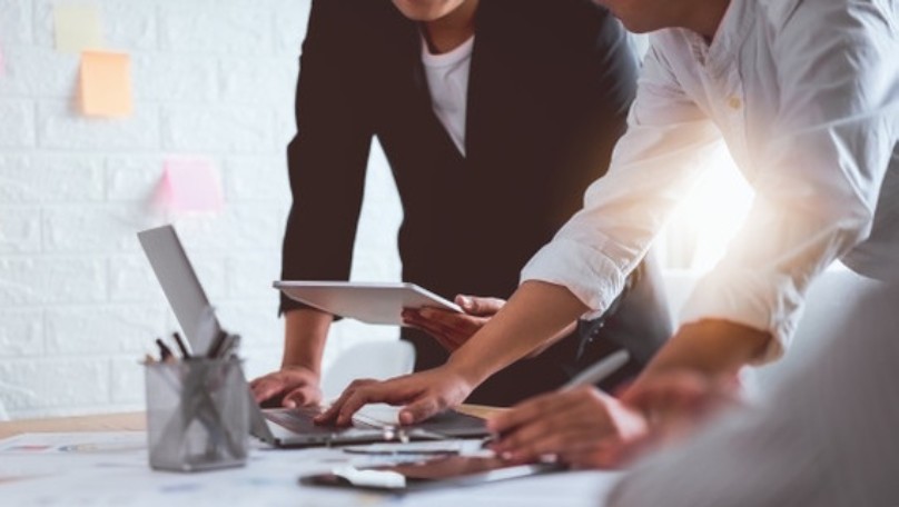 Dve osobe koje diskutuju i gledaju u laptop