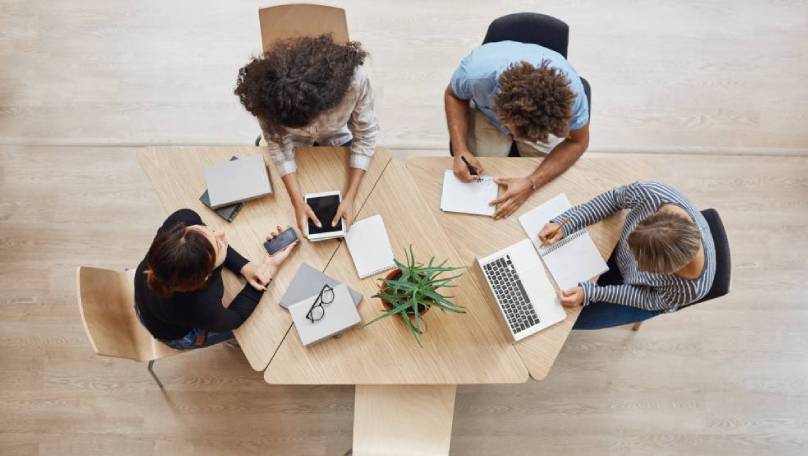 Slika ljudi za stolom koji se usavršavaju na online seminaru