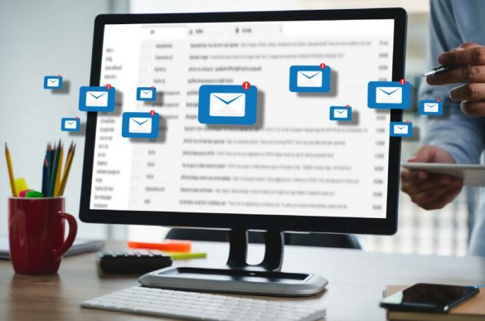 Ekran računara sa plavim ikonicama mailova koji izlaze iz njega